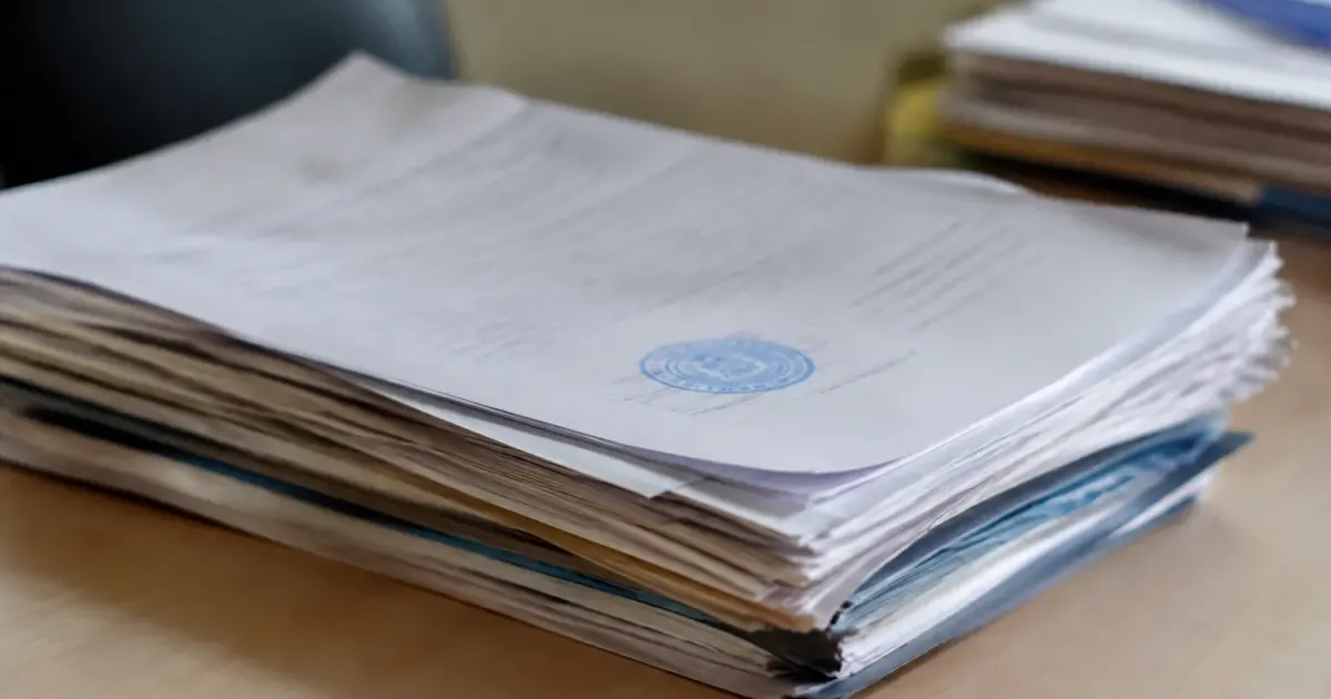 Documents administratifs empiles montrant tampon officiel